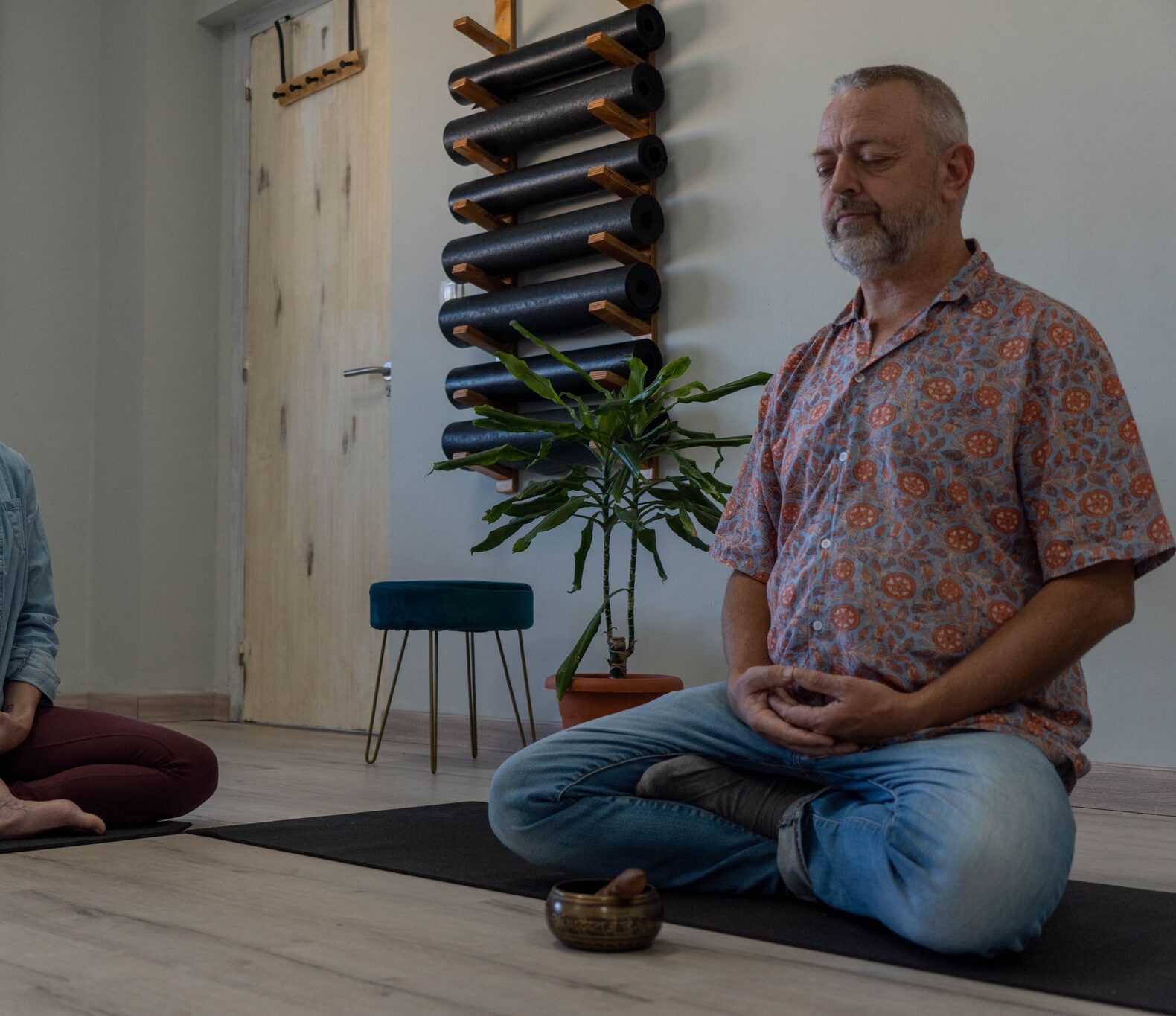 Hombre y mujer meditando en una sala con esteras de yoga.