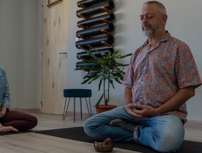Hombre y mujer meditando en una sala con esteras de yoga.